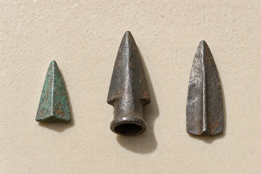 Wissenschaftliche Rekonstruktion und Vergleich von drei antiken Pfeilspitzen der Skythen, Römer und Kelten auf einer hellen Steinfläche im Museumslicht.